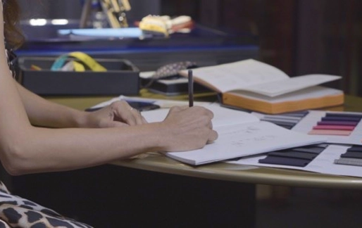 Person writes in a notebook at a table