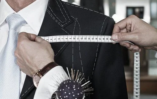 Tailor measures a man's shoulder with a tape