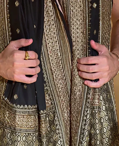 Hands holding a richly embroidered black and gold shawl
