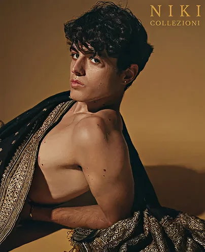 Man draped in a richly embroidered black and gold shawl