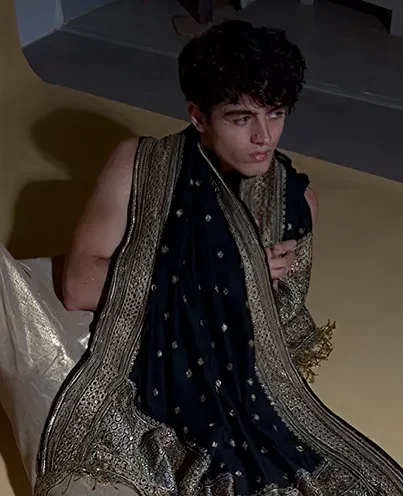 Man draped in a richly embroidered black and gold shawl