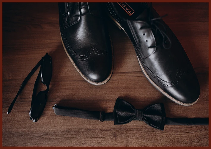 Flat lay of shoes, sunglasses, and bow tie.